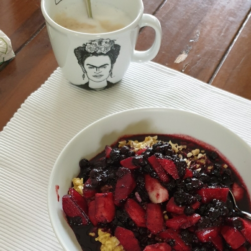 Porridge mit Beeren, Kaffee in einer Tasse mit dem Bild von Frida Kahlo