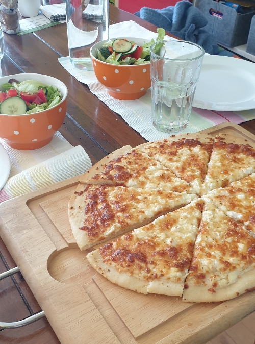 Pizza Bianca und Salat auf dem Esstisch