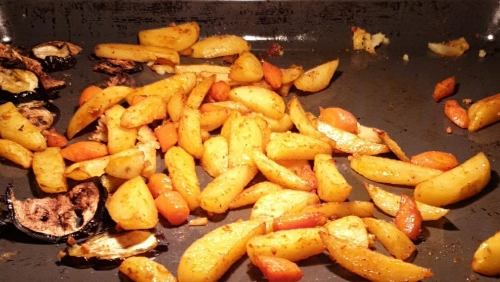 Auf einem Blech im Ofen brutzeln Kartoffel-, Süßkartoffel- und Kürbisstücke