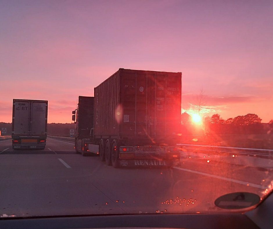Auf dem Bild drei LKW, durch eine violette Brille fotografiert. Die Tochter der Autorin macht während der Fahrt die Fotos.