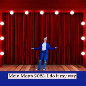Silke Geissen steht lachend auf einer Bühne, unter ihr auf einem Farbstreifen der Titel: Mein Motto 2023: I do it my way