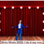 Silke Geissen steht auf einer Bühne mit rotem Vorhang und der Unterschrift "Mein Motto 2023: I do it my way