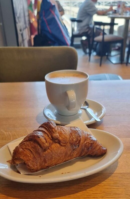 Eine Tasse Cappuccino und ein Croissant auf einem Tisch in einem Café