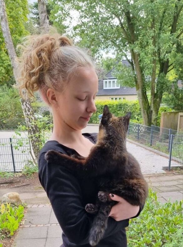 Eine junge Frau hält liebevoll eine Katze auf dem Arm