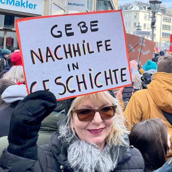 Birgit Ising, Autorin und Bloggerin, demonstriert gegen rechts. In der Hand hält sie ein selbstgemaltes Plakat mit der Aufschrift "Gebe Nachhilfe in Geschichte".