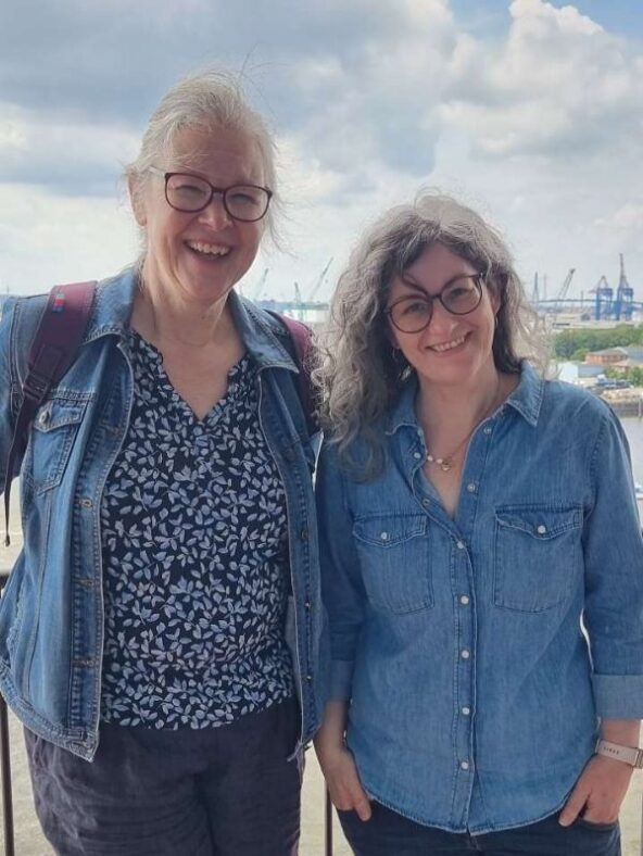 Zwei Frauen stehen lachend am Geländer der Elbphilharmonie-Plaza.