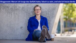 Die Autorin sitzt entspannt auf dem Boden, angelehnt an eine Betonwand, und neben ihr steht ein Kaffeebecher. Das Wetter ist sonnig, sie wirkt sehr entspannt. Über dem Foto ein blaues Banner mit der Schrift "Blogparade: Warum ich lange das Gefühl hatte, falsch zu sein, und was ich heute denke"