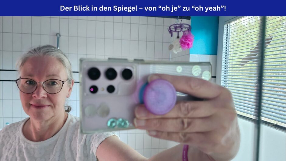 Eine Frau sieht lächelnd in den Spiegel, in dem sich auch ihr Handy spiegelt, mit dem sie gerade ein Spiegelselfie macht. Oben im Bild ein blaues Banner mit weißer Schrift: Der Blick in den Spiegel – von oh je zu oh yeah!