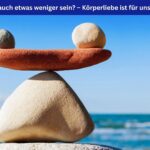 Gestapelte Steine am Meer. Auf einem länglichen Stein balancieren ein kleiner und ein größerer Stein im Gleichgewicht – Symbolbild für Körperliebe in jede Richtung. Oben im Bild ein blaues Banner mit weißer Schrift: Darf’s auch etwas weniger sein? – Körperliebe ist für uns alle da