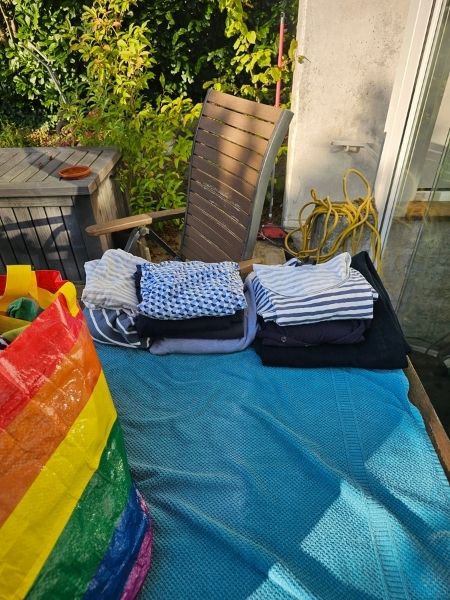 Auf einem Tisch im Garten liegt ein Handtuch, auf dem Kleidung gefaltet wird.