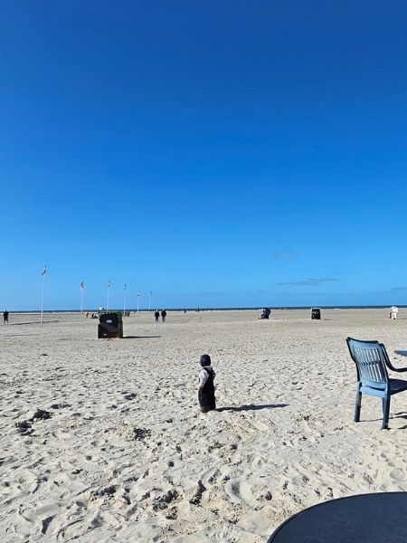 Die Enkelin der Autorin steht unternehmungslustig im Sand und überlegt, was sie als nächstes tun will.